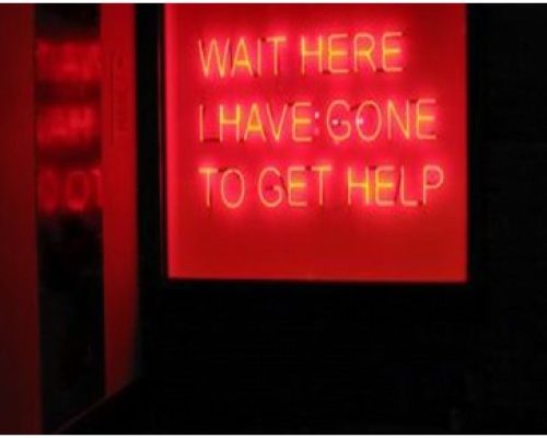 Neon sign reading "WAIT HERE I HAVE GONE TO GET HELP," illuminated in red, reflecting the contemporary art context of Midas Productions' power solutions for events.