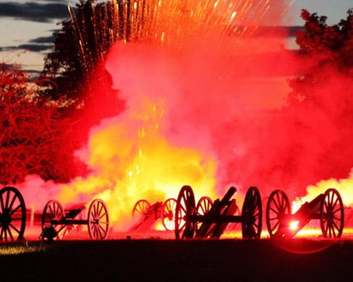 Cannon firing with explosions and colorful smoke at an outdoor event, illustrating Midas Generator Hire's power solutions for large-scale festivals.